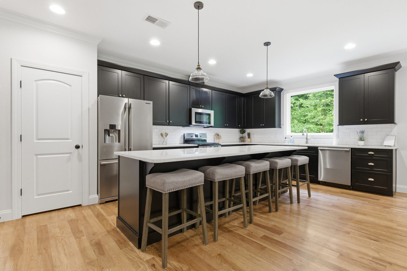 Full chef's kitchen with a large island, dark cabinetry, and stainless appliances